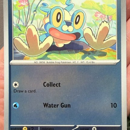 Carta individual Pokémon Froakie Reverse 020/086, Common, Basic, 70 HP, set ME4 Chaos Rising. Ilustración de Froakie apoyando sus manos sobre el recuadro sobre hojas de loto por Kariya - Thunder Cards México.